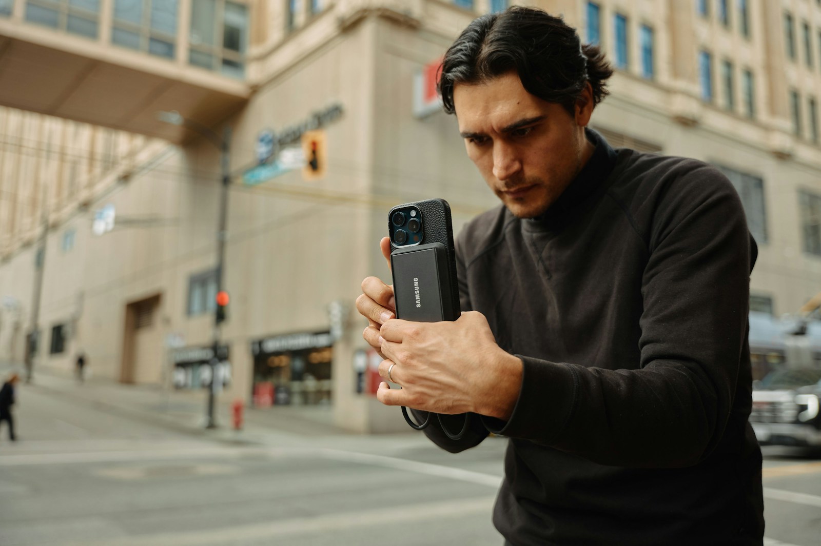 A man standing on the street looking at his cell phone